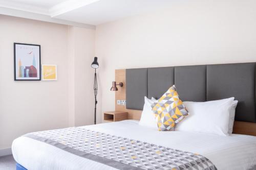 a bedroom with a large bed with white sheets and pillows at Holiday Inn Leicester City by IHG in Leicester
