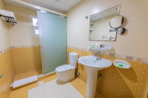 La salle de bains est pourvue de toilettes, d'un lavabo et d'un miroir. dans l'établissement Ewan Tower Hotel Apartments, à Ajman