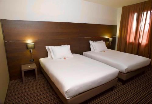 two beds in a hotel room with white sheets at Sweet Hotel in Longa