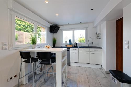 une cuisine avec des placards blancs et un îlot blanc avec des tabourets dans l'établissement Le Coeur des Alpes, à Marnaz