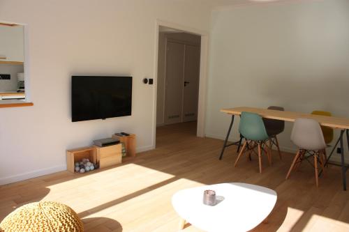 a living room with a table and a television at Appartement Knokke, vlakbij het strand en winkels in Knokke-Heist