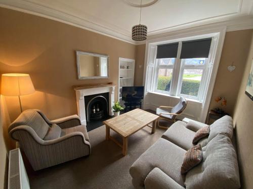 a living room with a couch and chairs and a fireplace at Roy Place Gdn Apartment in Campbeltown