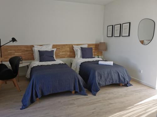 a bedroom with two beds with blue comforters at Casa das Portas in Azinhaga