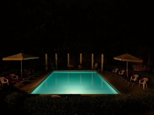 a swimming pool at night with chairs and umbrellas at Park Hotel Fantoni in Tabiano