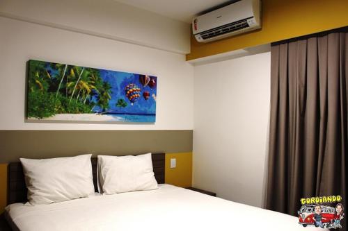 a bedroom with a bed with a white bedspread and a painting at Apartamento Resort em Olímpia in Olímpia
