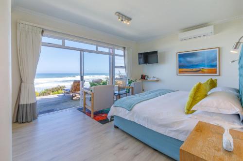 een slaapkamer met een bed en uitzicht op de oceaan bij Dune Beach House in Wilderness