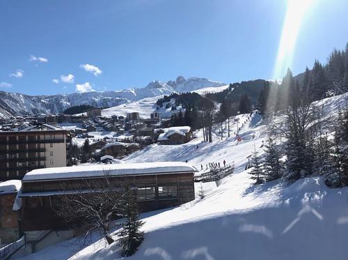 a snow covered mountain with a building and a town at Luxueux appartement skis aux pieds, jacuzzi privatif in Courchevel