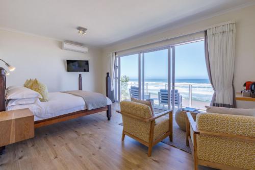 a bedroom with a bed and a view of the ocean at Dune Beach House in Wilderness