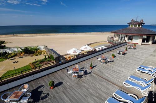 a deck with chairs and tables on the beach at Hotel Apollo in Darłówko