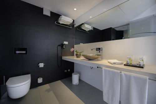 a bathroom with a toilet and a sink with towels at Hotel Garbi Ibiza & Spa in Playa d'en Bossa