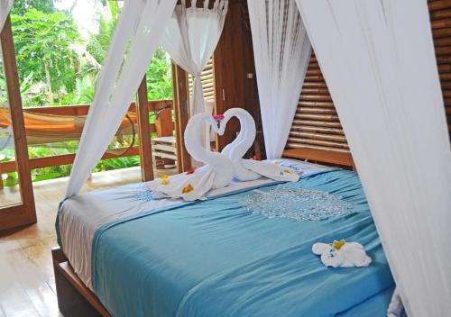 two swans are sitting on top of a bed at Lagoona Beach Bungalows - Eco Resort Batukaras in Batukaras