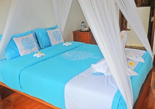 a bedroom with a blue bed with a canopy at Lagoona Beach Bungalows - Eco Bungalows Batukaras in Batukaras