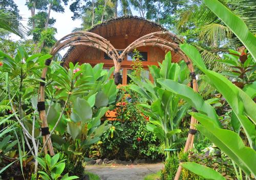 a garden with green plants and a wooden building at Lagoona Beach Bungalows - Eco Bungalows Batukaras in Batukaras