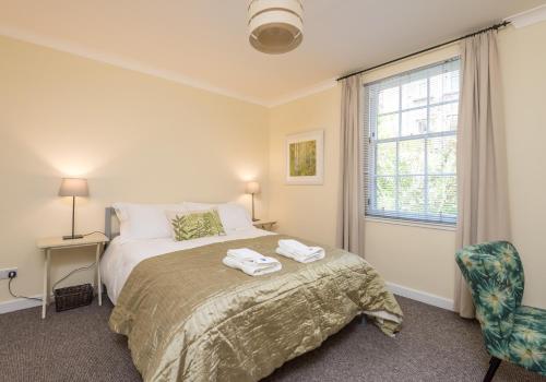 1 dormitorio con cama, ventana y silla en Castle Suite 3 Old Town, en Edimburgo