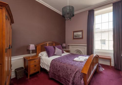 a bedroom with a bed with purple sheets and a window at Bank St Royal Mile in Edinburgh