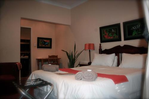 a bedroom with a bed with two towels on it at Amper Bo Guest House in Pretoria