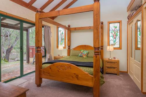 a bedroom with a wooden bed in a room with windows at Yelverton Brook Conservation Sanctuary in Metricup