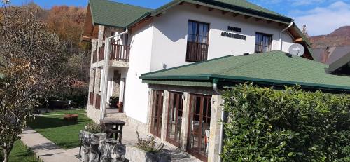 a white house with a green roof at Rooms and apartmants Mirovic in Kolašin