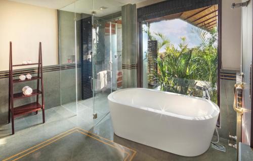 a bathroom with a large tub and a glass shower at Niraamaya Wellness Retreats Backwaters And Beyond Kumarakom in Kumarakom
