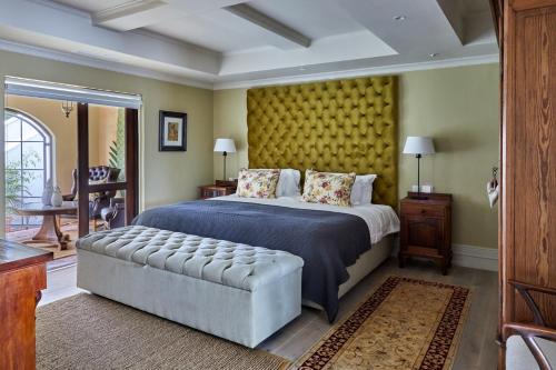 a bedroom with a large bed and a yellow wall at Deux Frères Wine Estate & Luxury Villas in Stellenbosch