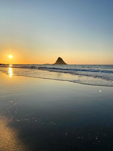 un tramonto su una spiaggia con una roccia nell'oceano di Midnattsol rom og hytter a Bleik