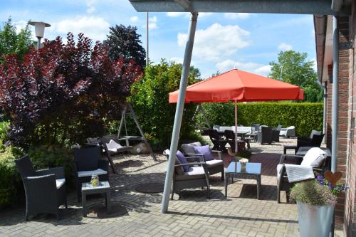 a patio with tables and chairs and an umbrella at Hotel Garni am Obsthof GbR in Stade