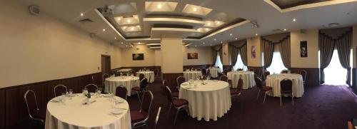 a room filled with tables and chairs with white linens at Hotel Golden Tulip Varna in Varna City