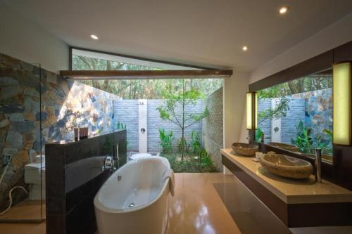 ein großes Bad mit einer Badewanne und einem großen Fenster in der Unterkunft FLAMINGOS DAI LAI RESORT - luxury in Ngọc Quang