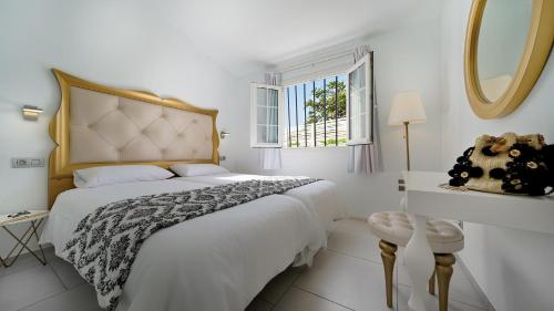 a white bedroom with a large bed and a window at Bungalows Adonis in Playa del Ingles
