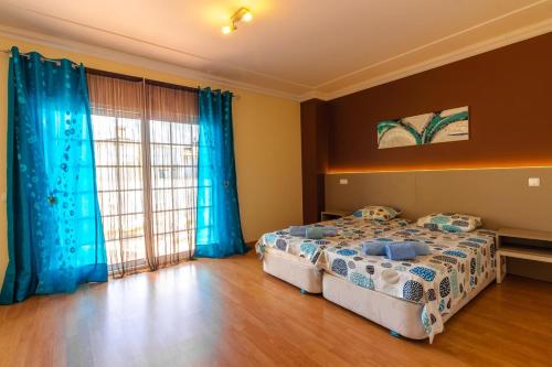 a bedroom with two beds and blue curtains at Sergio s Place - FARM VILLAGE - By Algarkasa in Albufeira