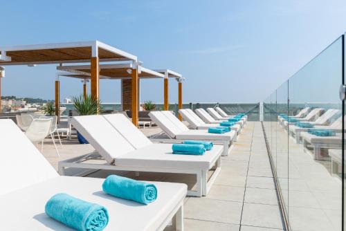 a row of white lounge chairs on a roof at L'Azure Hotel 4* Sup in Lloret de Mar