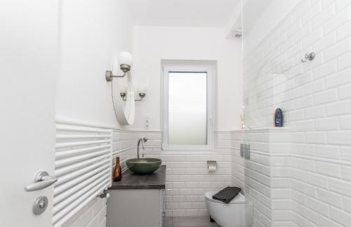 uma casa de banho branca com um lavatório e um WC em Vinorell Apartman em Etyek