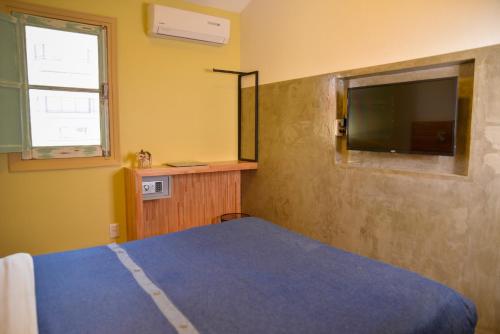 a bedroom with a bed and a flat screen tv at TAS D VIAJE Suites - Hostel Boutique in Punta del Este