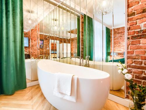 a bathroom with a white tub and a green curtain at Fancy Apartment Nikiszowiec in Katowice