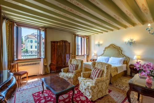 1 dormitorio con 1 cama, 2 sillas y mesa en Ca' dei Cuori on the Grand Canal, en Venecia