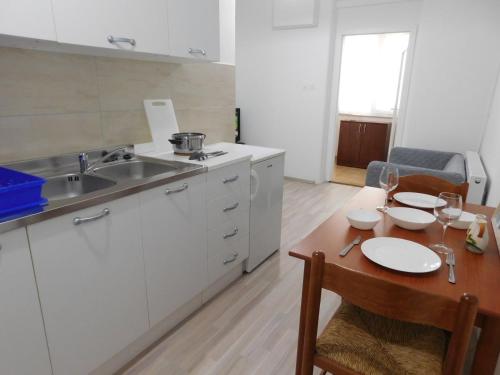 a kitchen with white cabinets and a wooden table at Apartments Mateo in Zagreb