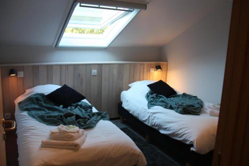 two beds in a small room with a skylight at Le Refuge d'Engreux in Houffalize