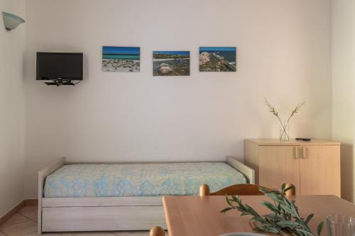 een slaapkamer met een bed en een tv aan de muur bij Le Dimore di Budoni in Budoni