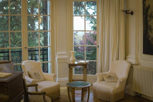sala de estar con 2 sillas, mesa y ventanas en La Villa by Michel Gonet, en Épernay