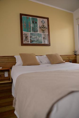 a bedroom with a white bed and a picture on the wall at TAS D VIAJE Suites - Hostel Boutique in Punta del Este