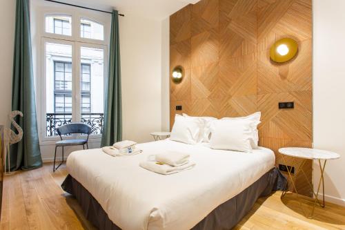 Schlafzimmer mit einem großen Bett mit einem Kopfteil aus Holz in der Unterkunft CMG-Champs Elysées - Boetie 8 in Paris