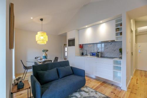 a living room with a blue couch and a kitchen at LovelyStay - Downtown Studio with Pool, AC and Balcony in Porto