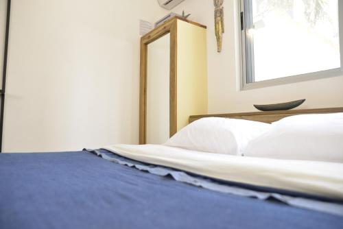 a bedroom with a bed with white sheets and a mirror at TAS D VIAJE Suites - Hostel Boutique in Punta del Este