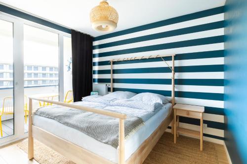 a bedroom with a blue and white striped wall at Chill and Sun in Kołobrzeg