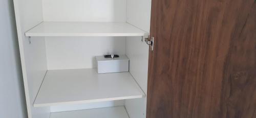 a white closet with white shelves and a wooden door at Di Raffaele Bombinhas in Bombinhas