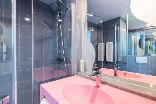a bathroom with a pink sink and a shower at Prize by Radisson, Rostock City in Rostock