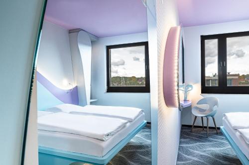 a room with two beds and a table and two windows at Prize by Radisson, Rostock City in Rostock