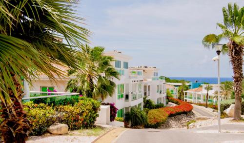 a large white building with palm trees and the ocean at Piscadera Harbour Village in Willemstad