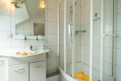 ein Bad mit einem Waschbecken und einer Dusche in der Unterkunft Ferienhaus Butenbörkumer in Borkum