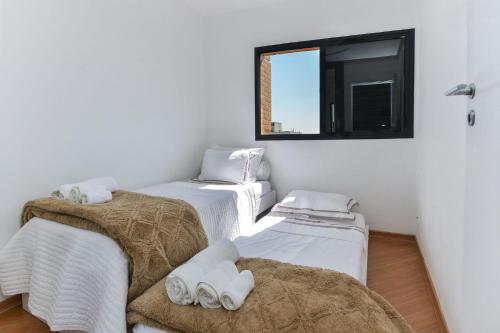 a room with three beds and a window at Apartamento Aconchegante com Vista Incrível, Piscina e Vaga in São Paulo